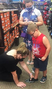 2 students trying on shoes with sales clerk
