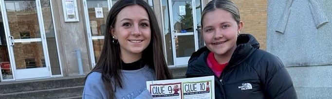 students holding a sign with clues