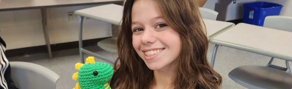 student holding a crocheted dragon